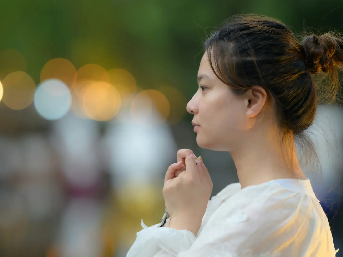 A woman holding her hands together in quiet prayer outdoors