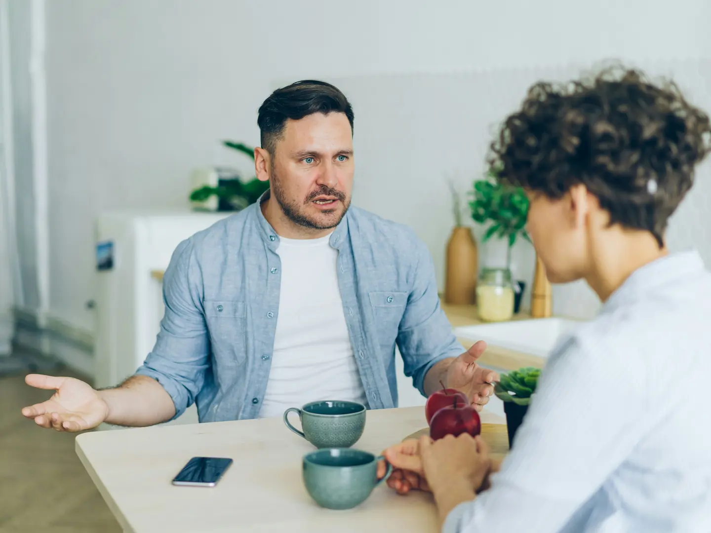 Two adults having a serious conversation across a table