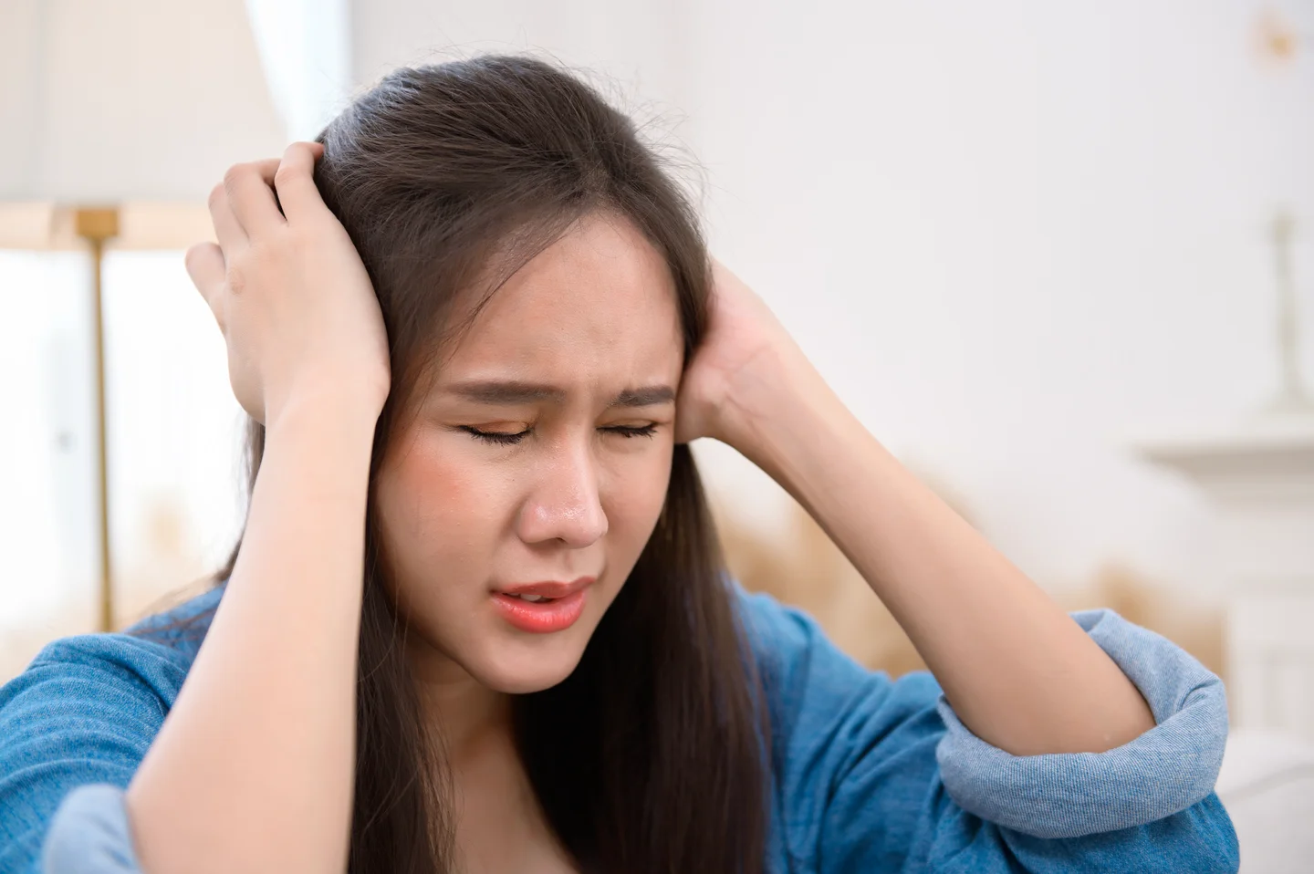 A woman with her eyes closed holding both sides of her head