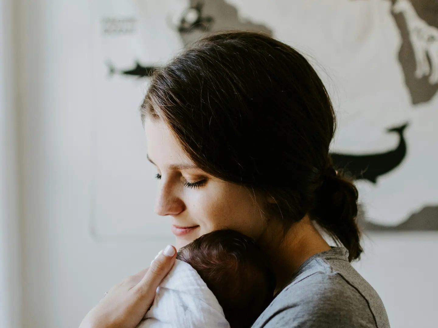 A woman holding a newborn against her shoulder at home
